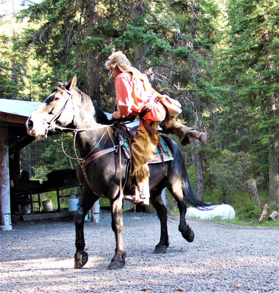 Buckskin, the mountain man, enters camp on his horse to meet the folks.